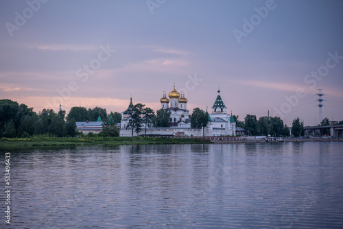 an old white-stone monastery on the banks of the river on a summer day
