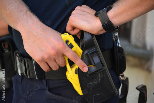 Policjant na służbie z elektrycznym paralizatorem. Tazer. Taser