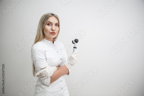 Portrait of blonde woman dermatologist with dermatoscope in white lab coat and white gloves on the white background