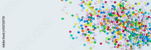 Banner with colorful beads scattered on a blue background. Equipment for handmade accessories.