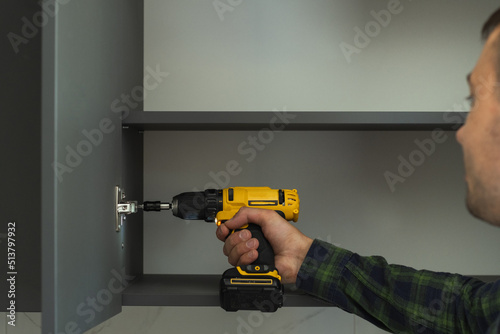 Furniture maker uses a screwdriver to attach a door to a cabinet. New furniture assembling