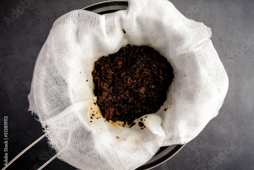 Used Coffee Grounds in a Cheesecloth Lined Strainer: Coffee grounds leftover after straining cold brew