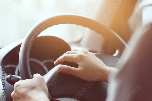 Close up shot of a man's hands holding a car's steering wheel and honking the horn on the road.