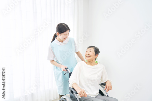室内で車椅子に乗る高齢者女性と笑顔で会話する介護士