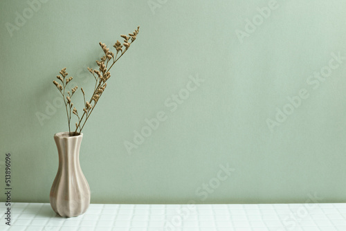 Vase of dry flowers on white table. khaki green wall background