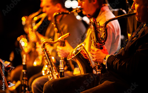 Big Band: the sax section. Focus on the foreground baritone saxophone. From a series of images of musicians in a swing Jazz band.