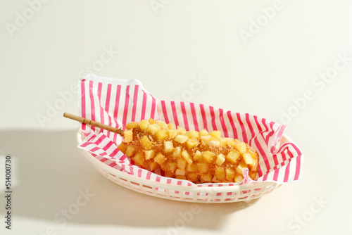 Delicious Crunchy Korean Style Chunky Potato Corn Dogs with Batter and Fried Potatoes. Isolated on Cream Background
