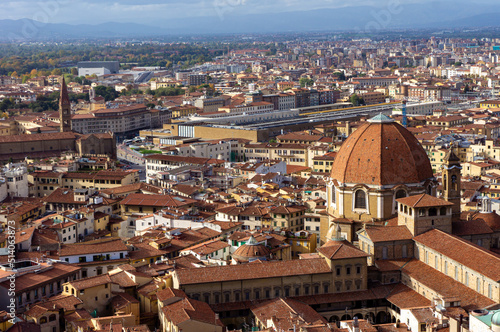 Aerial view of Florence, Italy on a sunny day with beautiful red rooftops of ancient houses and streets. Panoramic view of Basilica of San Lorenzo and Train station.