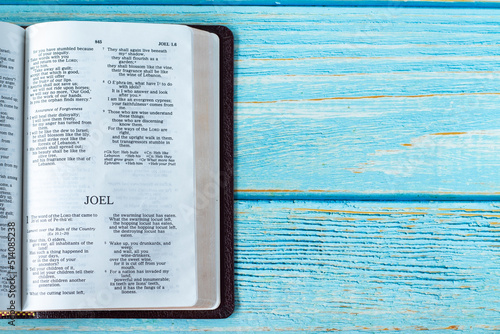 Joel open Holy Bible Book on a rustic wooden background with copy space. Top table view. Old Testament Scripture prophecy study, Christian biblical concept. 