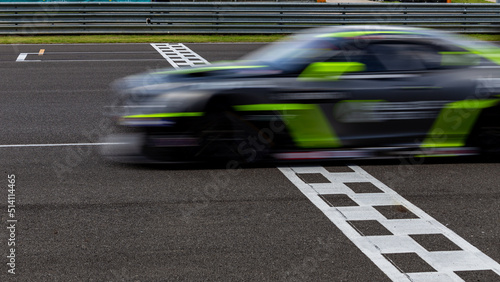 Race car blurred motion crossing the finish line on international circuit speed track, Motion blur Racing car crossing finish line on asphalt main straight racetrack.