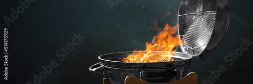 New modern barbecue grill with burning firewood on dark background. Banner design