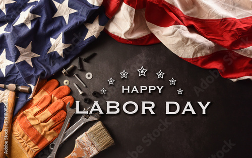 Happy Labor day concept. American flag with different construction tools and the text on dark stone background.