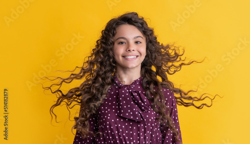 happy girl with long brunette curly hair on yellow background