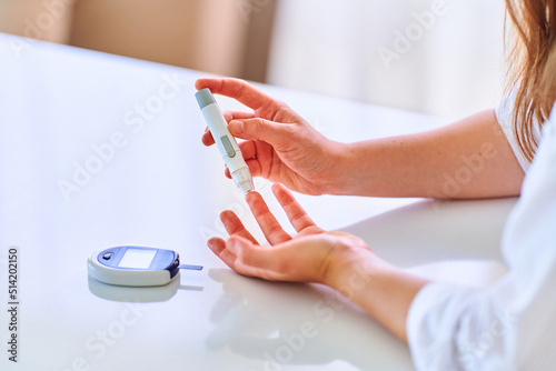 Female using lanceter on finger for measuring and checking blood glucose level. Healthcare and mellitus diabetes treatment