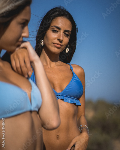 two girls in bikini spending a day on the beach at sunset