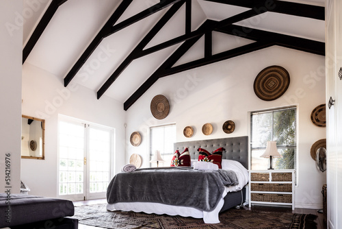 Empty neat bed with blankets and pillows under mansard roof in modern bedroom, copy space