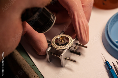 Watch repair at watchmaker wiyh magnifying glass. Focus on date disc inside case. Maintenance of clockwork. Selective focus close-up image.