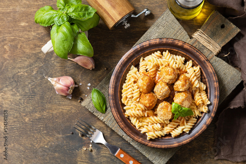 Italian homemade kitchen. Italian fusilli pasta gluten freewith meat balls in tomato sauce and basil on rustic table. View from above. Copy space.