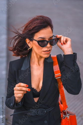 Fashion pose. Gorgeous brunette girl in the city with sunglasses looking at the camera