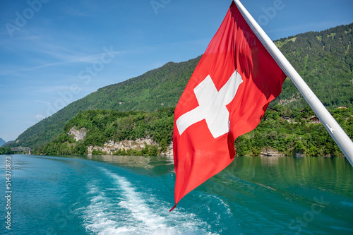 Swiss flag over landscape of lake Brienz. Interlaken, Switzerland.