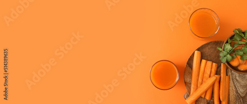 Glasses of fresh carrot juice on orange background with space for text