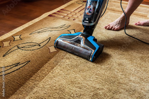 Cordless vacuum cleaner is used to clean the carpet in the room.