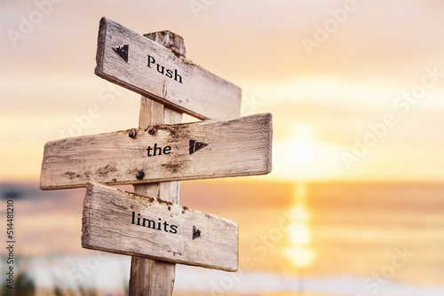 push the limits text quote on wooden crossroad signpost outdoors on beach with pink pastel sunset colors. Romantic theme.