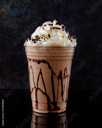 Chocolate milkshake served in a clear glass on a dark background. Isolated drink.