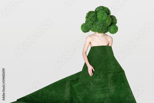 a naked young guy in a mask in the form of a huge broccoli is hiding behind an artificial turf