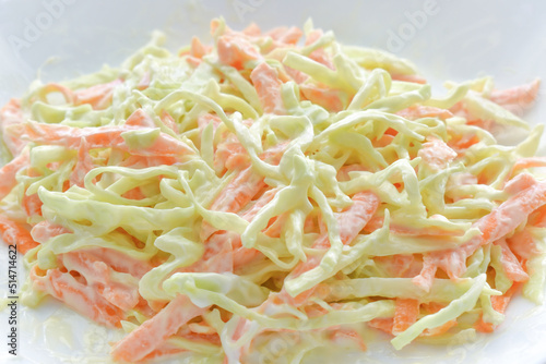 Creamy coleslaw salad with carrot, and cabbage on a white plate.