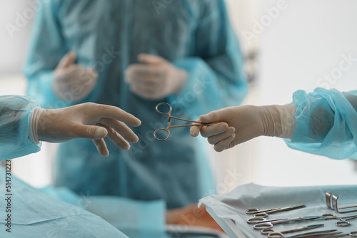 Assistant hands out instruments surgeon during surgery in the operating room