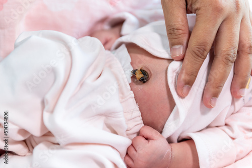 The mother's hand is placed on the body of a 7-day-old baby newborn, to expose the baby's umbilical cord, to children and health baby newborn concept.