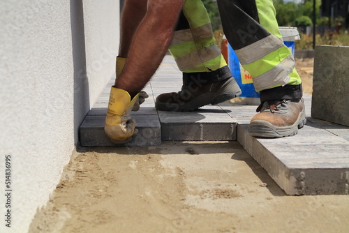 The paver places the paving stones on the prepared substrate. Na przygotowane podłoże brukarz układa kostkę brukową.