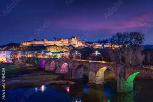 Medieval city of Carcassonne Pont Vieux bridge lit up at night during Christmas with pink clouds from the sunset