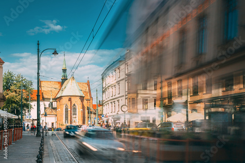 Krakow, Poland. Trams Motion Near Dominican Square. Traffic And Franciscan Monastery and Basilica of St. Francis of Assisi On Background.