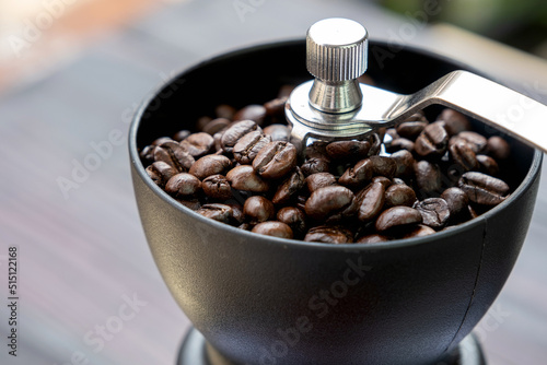 Coffee beans roasted in a manual coffee grinder on a wooden table, drip coffee maker