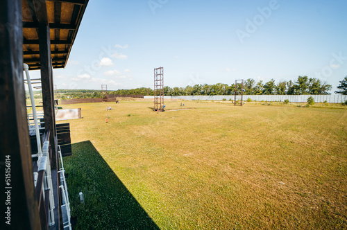 Empty shotgun training field with green grass and plat machines