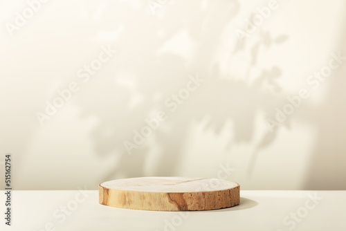 Wood slice podium with leaves and window shadows on beige background for cosmetic product mockup