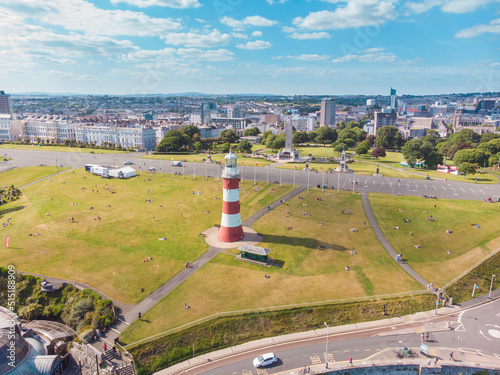 Aerial drone shot of a red and white striped lighthouse on the coast in Plymouth, UK