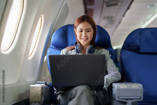 portrait of A successful asian business woman or female entrepreneur in formal suit in a plane sits in a business class seat and uses a computer laptop during flight