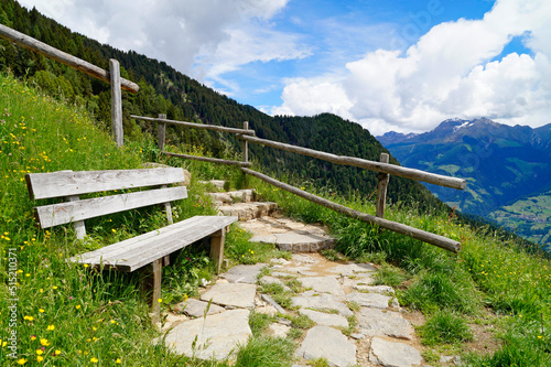 a bench overlooking the alpine valley of the city Merano surrounded by the Texel group mountains (Oetztaler Alpen in Südtirol, South Tyrol, Italy) 