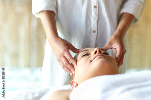 Relaxed woman receiving a facial massage by therapist