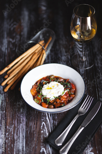 Appetizing dish on a dark wooden table. Vegetable stew with egg.