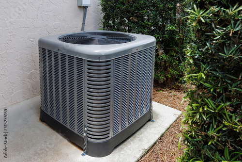 Modern HVAC air conditioner unit on concrete slab outside of house.