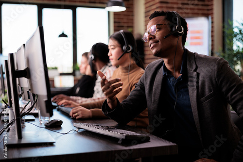 Reception secretary answering client phone call at customer service, helping people at call center support. Male receptionist giving telemarketing assistance on phone helpline in office.