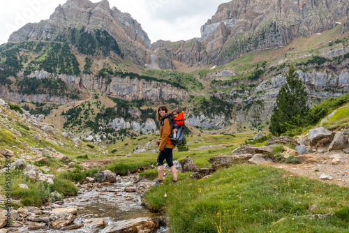 Woman with her son in the backpack walking in the Pyrenees in summer, Valle de Tena, Huesca