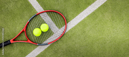 tennis balls and racket on green synthetic grass court background. top view with copy space