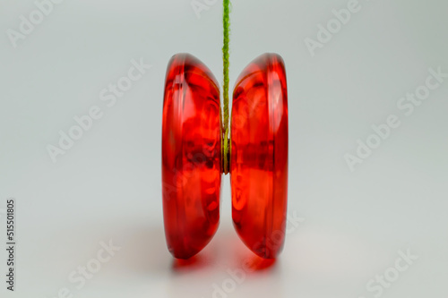 Red plastic yo-yo toy isolated on White Background with green rope attached to it.