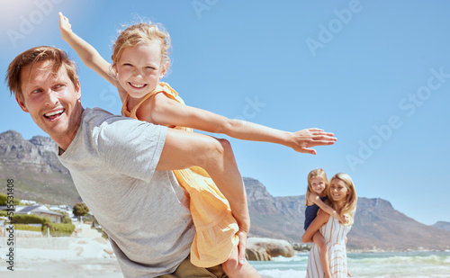 Smiling family with daughters on the beach. Happy man and woman bonding with young adorable girls on holiday. Cute siblings pretending to fly while being carried by their mother and father outside