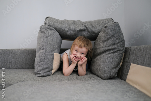 funny European child playing with pillows on couch